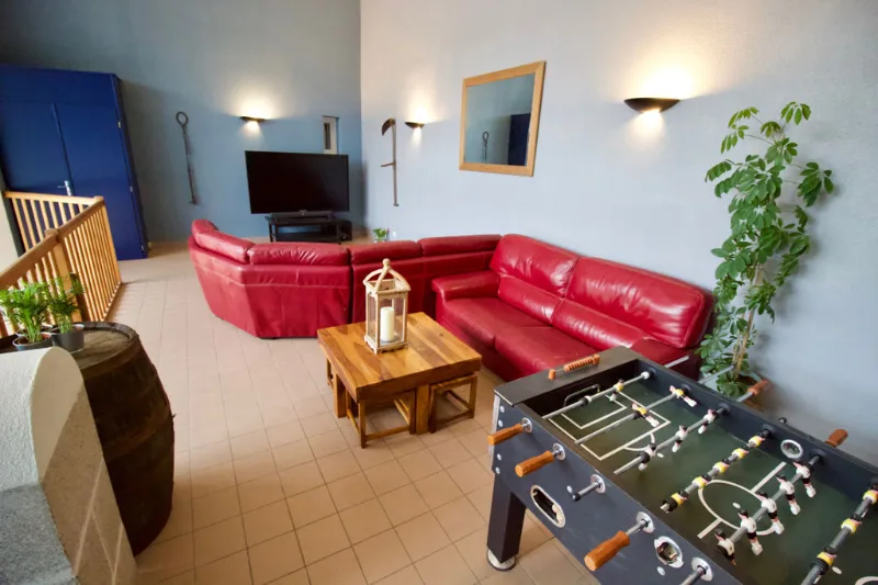 Salon de détente avec canapés en cuir rouge et baby-foot