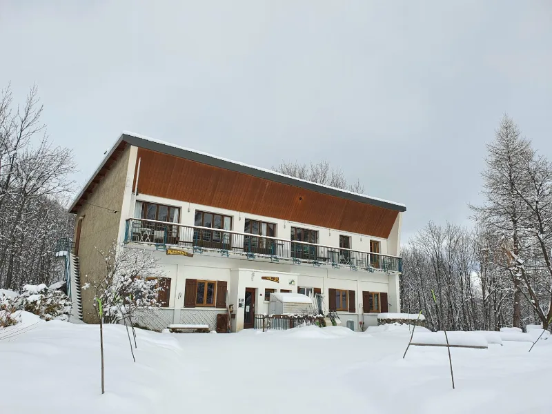 Façade du chalet Le Val d'Or par temps de neige, balcons filants sur toute la longueur
