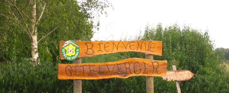 Panneau de bienvenue en bois à l'entrée du Gîte du Verger
