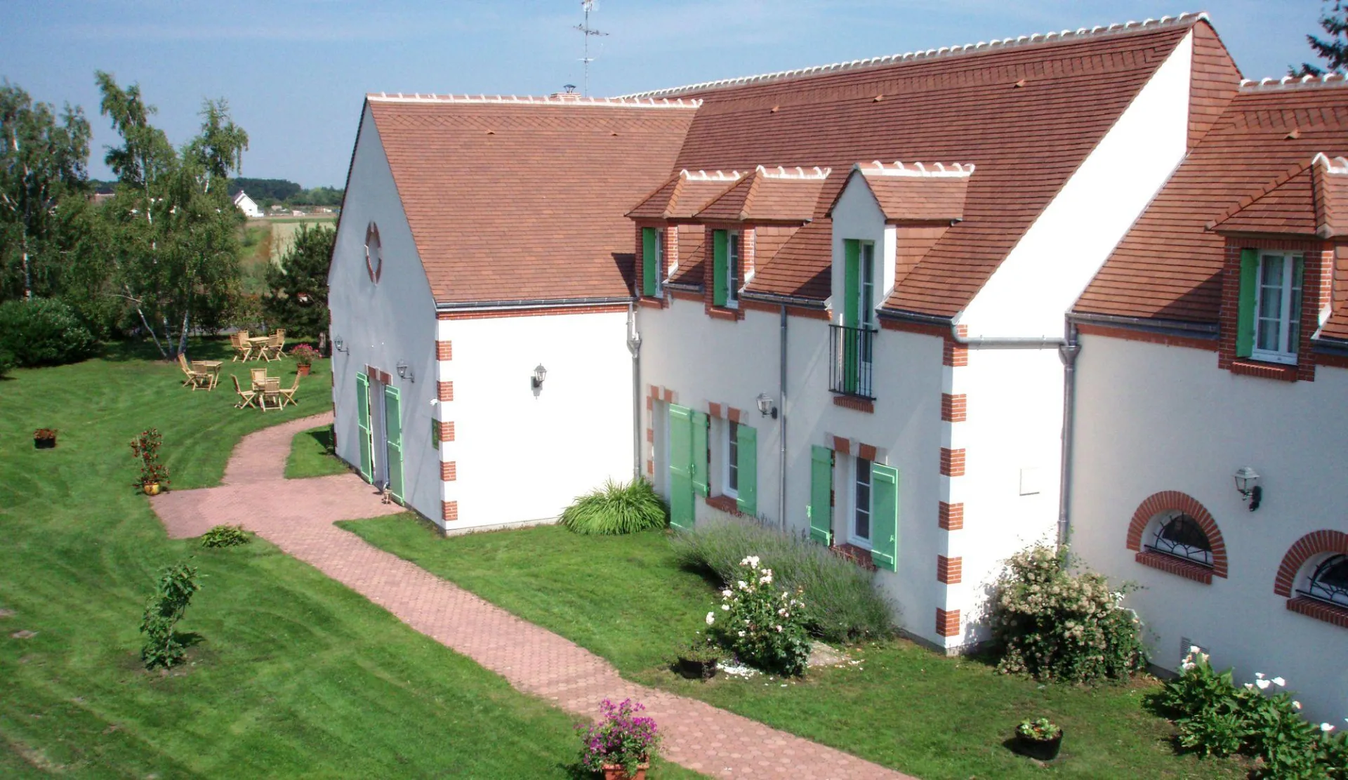 Gîte de groupe Le Gîte du Verger à Saint-Martin-d'Abbat — Façade en pierre du Gîte du Verger avec entrée principale et espace verger, capacité 53 personnes