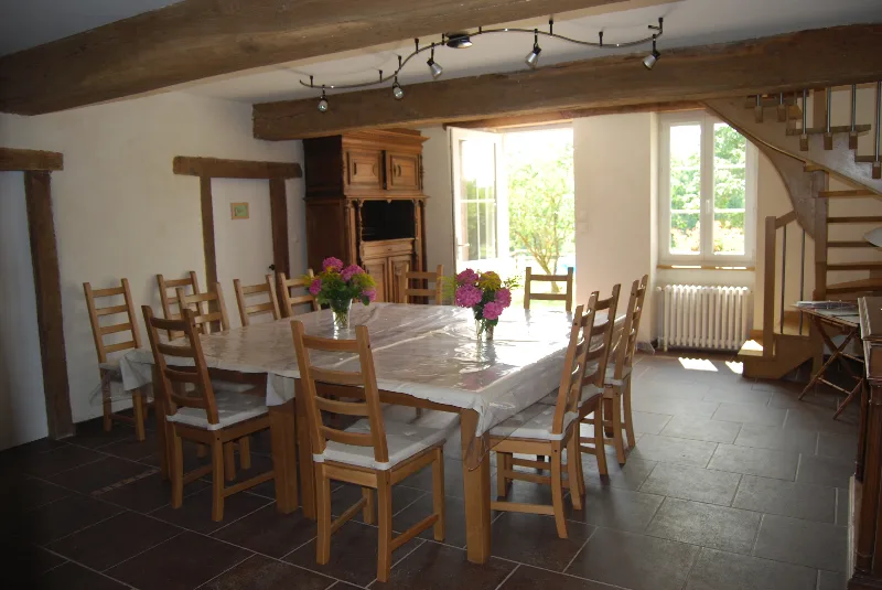 Grande salle de séjour lumineuse avec poutres apparentes et coin repas pour 12 personnes