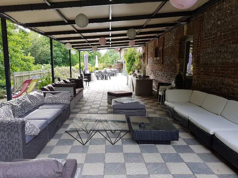 Salon extérieur couvert avec canapés en résine tressée et lampions colorés