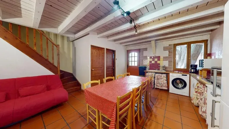 Cuisine équipée ouverte sur un coin repas et un salon, avec accès direct à la cour