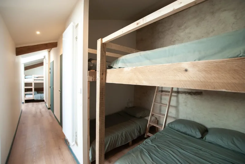 Couloir du dortoir avec lits superposés en bois, amenageable pour l'accueil de groupes nombreux