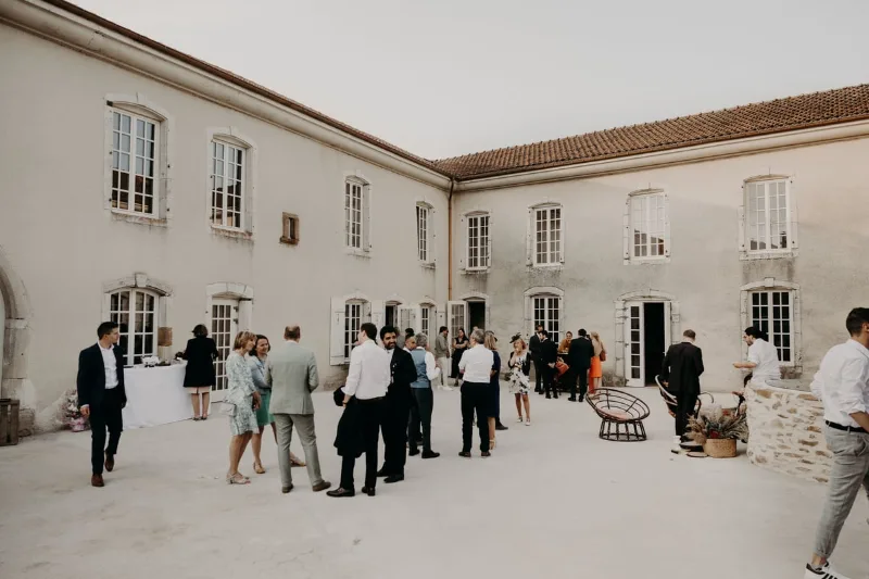 Cour intérieure du château-ferme accueillant une réception en plein air entre les bâtiments en pierre