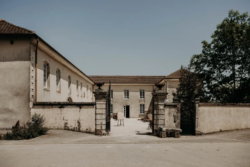 Façade en pierre du Château-ferme d'Aboncourt avec portail d'entrée et cour pavée