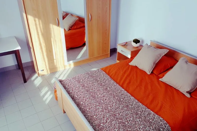 Chambre avec lit double et parure de lit orange, ambiance chaleureuse