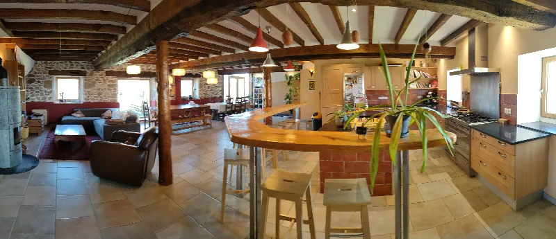 Grande pièce à vivre rustique et lumineuse du gîte de groupe Le Grand Roc avec salon et salle à manger