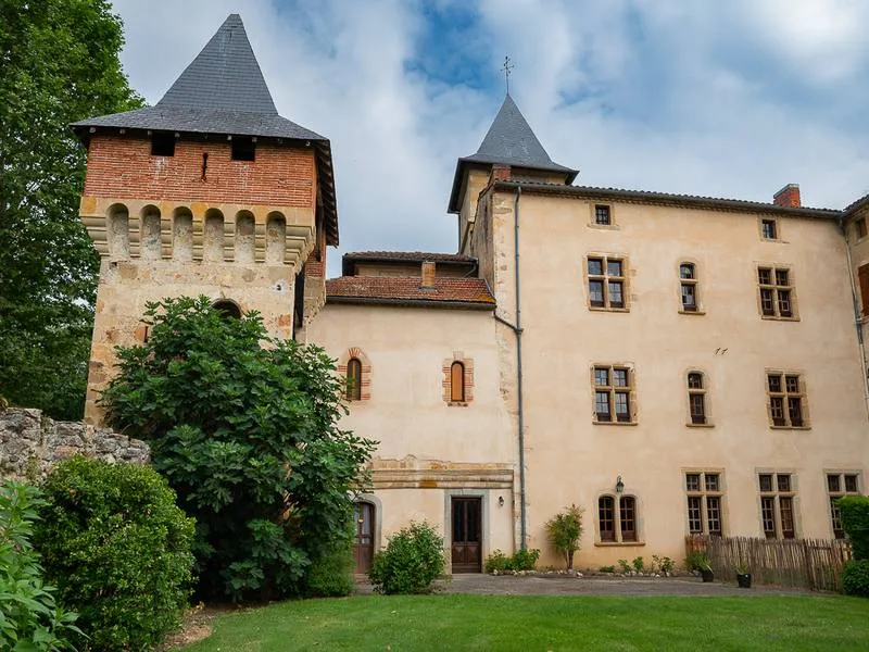 Gîte de groupe Le Grand Gîte du Château de la Hille à Montégut-Plantaurel — Façade du château avec sa tour ronde à mâchicoulis et sa tour carrée, entourée de verdure, capacité 15 personnes