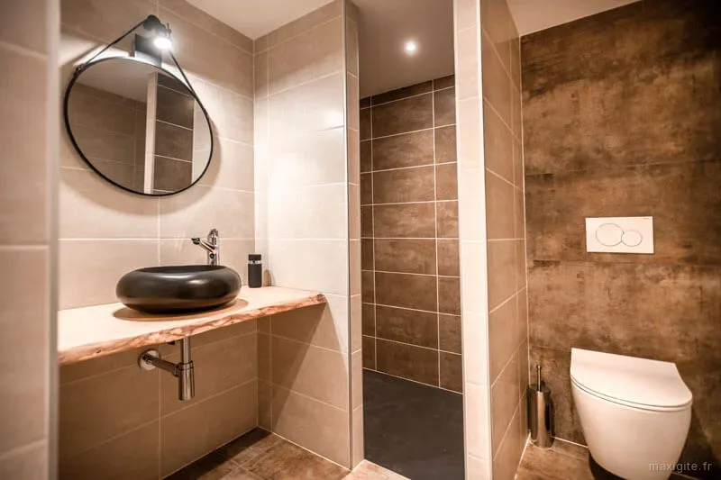 Salle d'eau moderne avec vasque noire sur plan en bois brut et douche à l'italienne