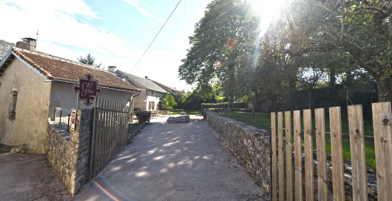 Entrée du gîte avec portail en bois et enseigne dans le village de La Cavalerie