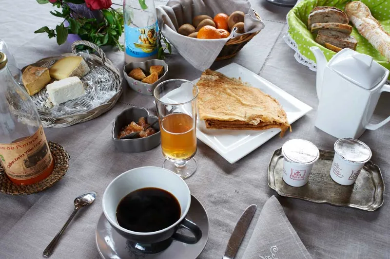 Petit-déjeuner breton avec crêpes, fromages, fruits et café