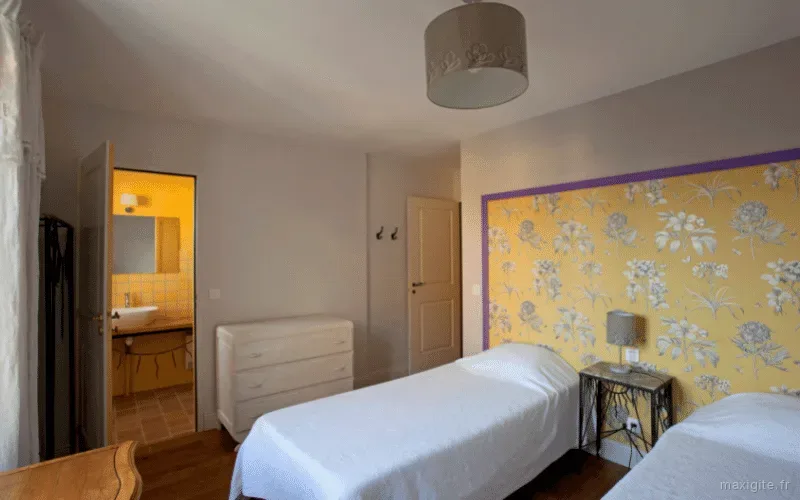 Chambre lumineuse aux tons jaunes avec commode et lits jumeaux