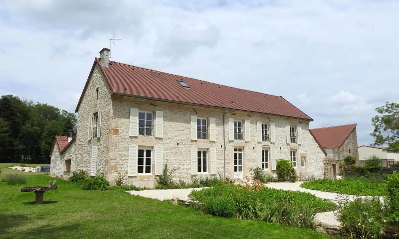 Façade en pierre du gîte avec toiture en tuiles et jardin arboré