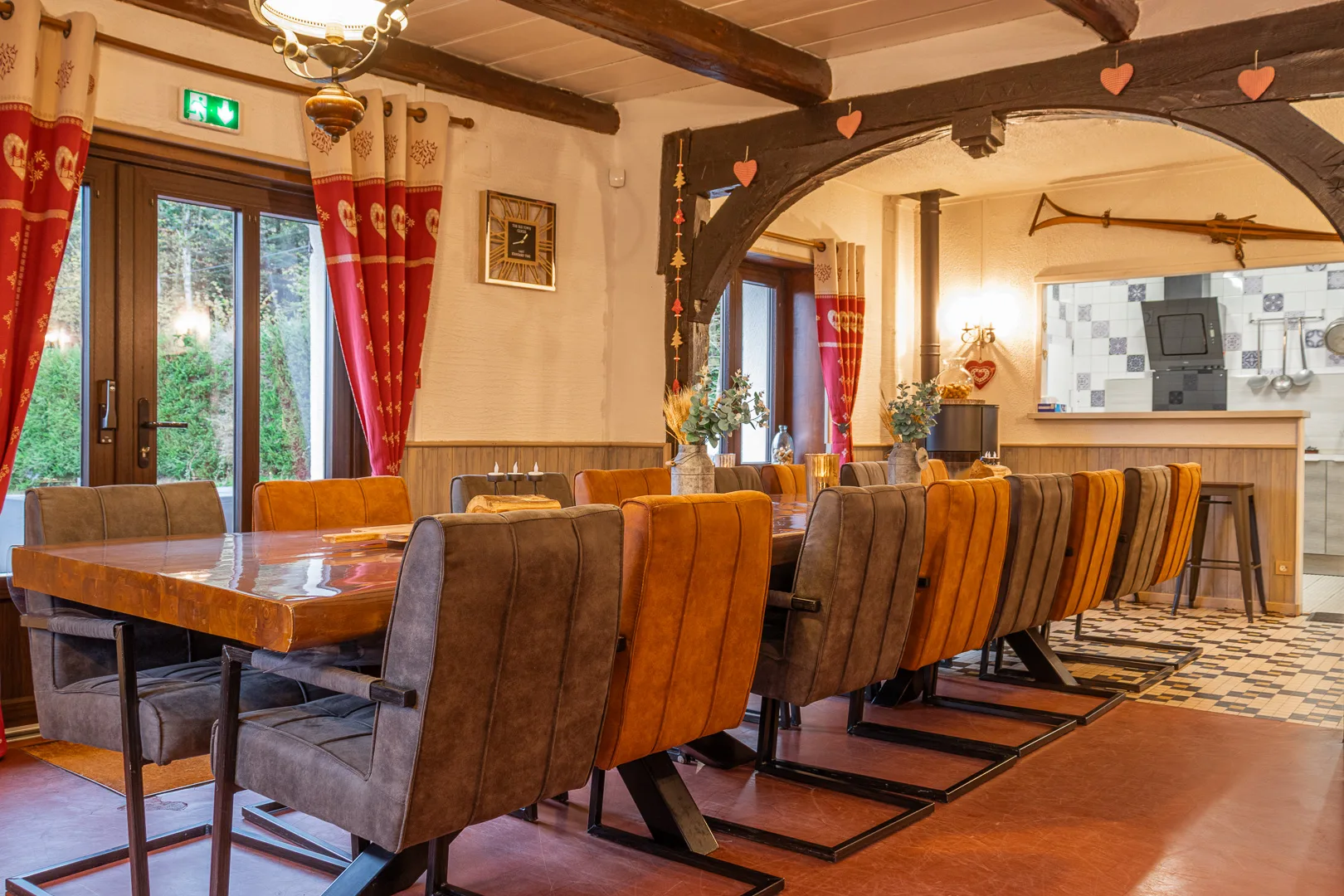 Gîte de groupe Gîte La Vosgienne à Sapois — Grande salle à manger avec table en bois massif et cuisine ouverte à l'arrière-plan, capacité 15 personnes