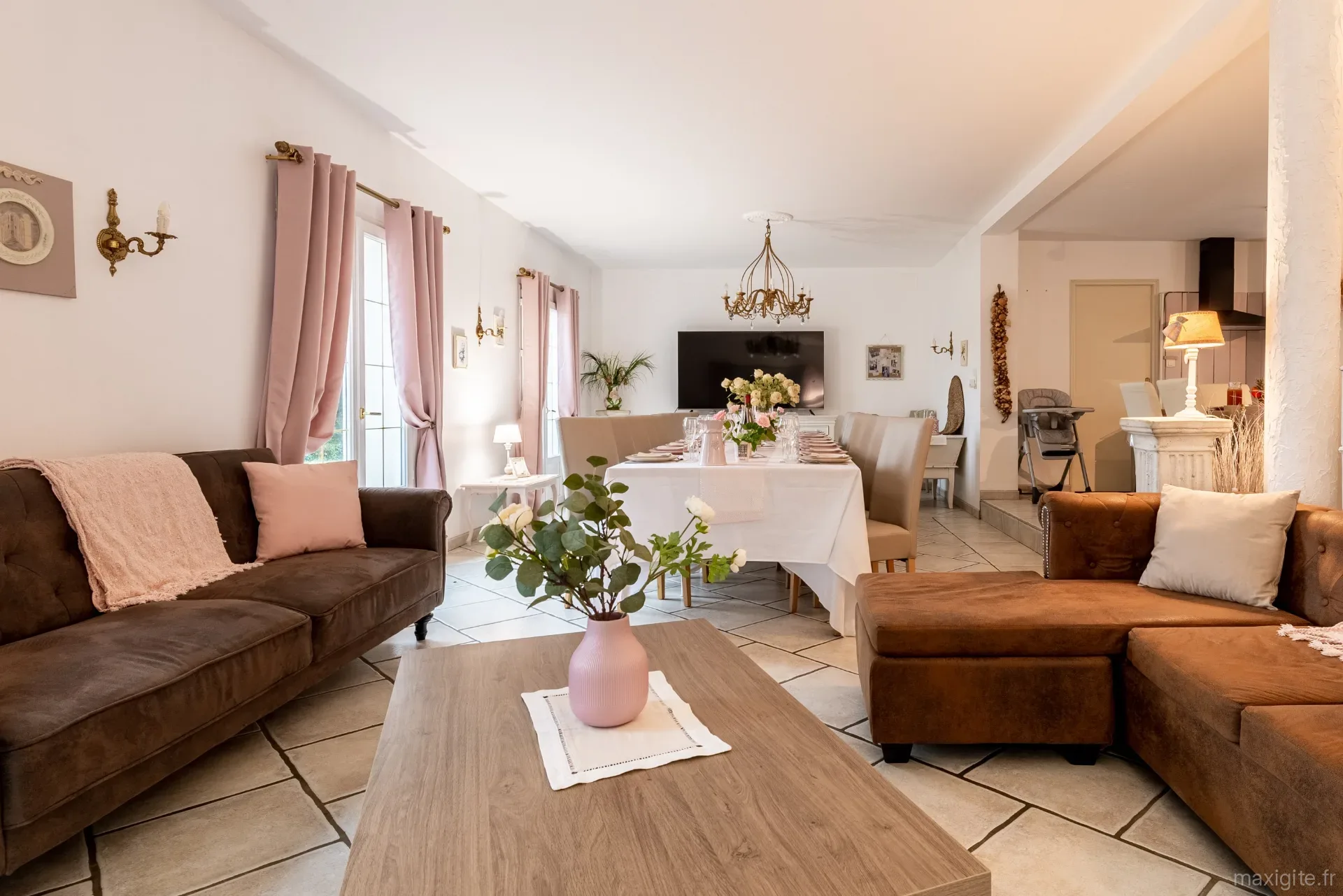 Grand séjour et salle à manger avec canapés et longue table dressée pour les convives