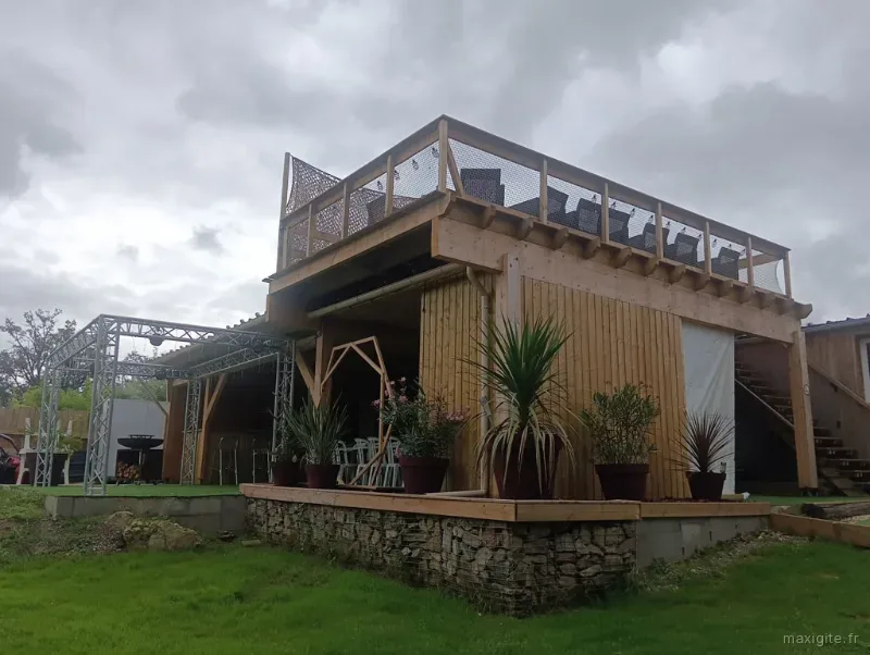 Façade en bois et pierre du Domaine de la Basse Marche avec terrasse et pots de plantes