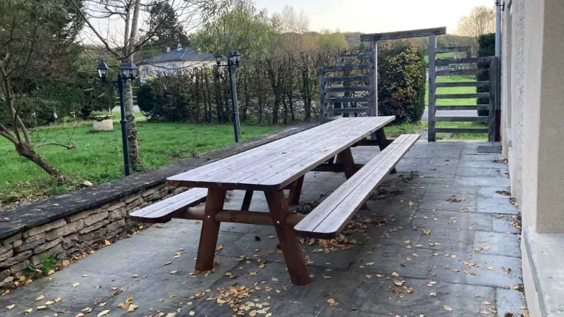 Longue table pique-nique en bois sur la terrasse extérieure du gîte