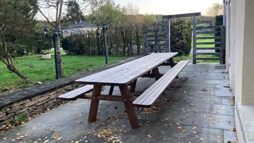 Longue table pique-nique en bois sur la terrasse extérieure du gîte