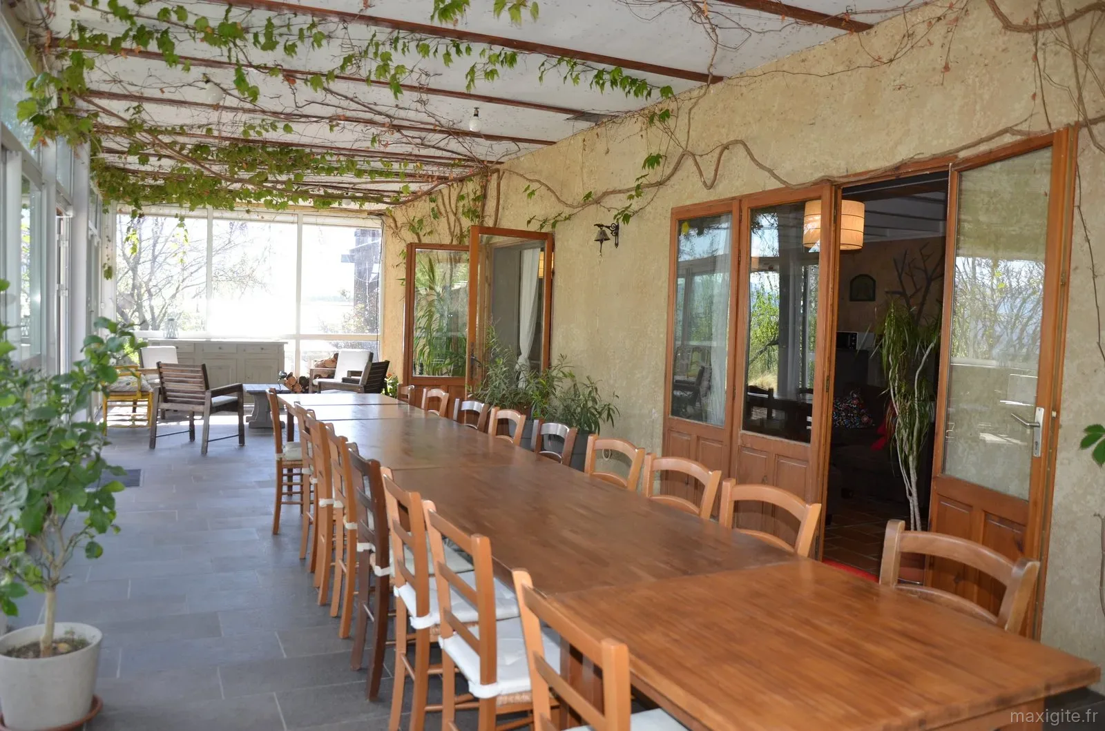Longue table en bois dressée pour un grand groupe dans la véranda ouverte sur le jardin