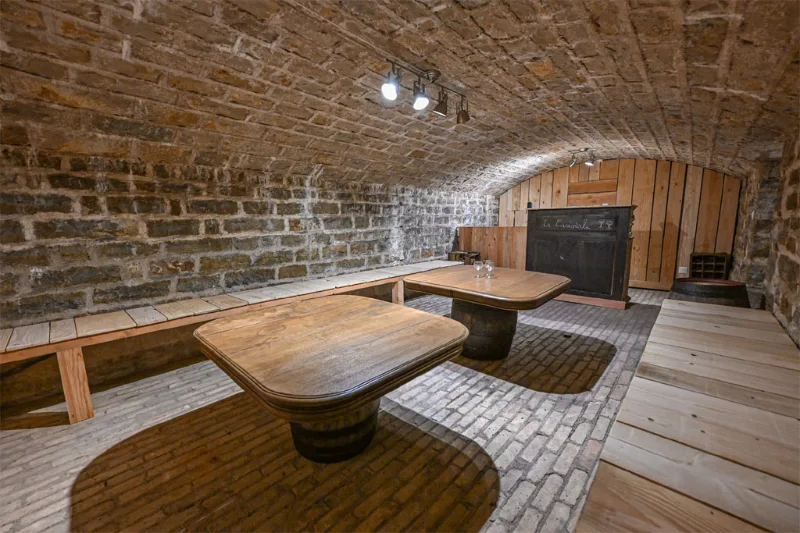 Cave de convivialité voûtée avec tables sur tonneaux pour dégustations