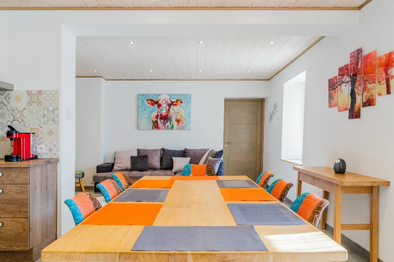 Salle à manger conviviale avec grande table en bois pour groupe et tableau d'une vache