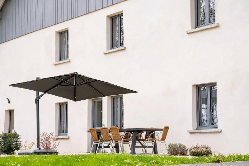 Terrasse extérieure ombragée avec grands parasols, table et chaises en rotin