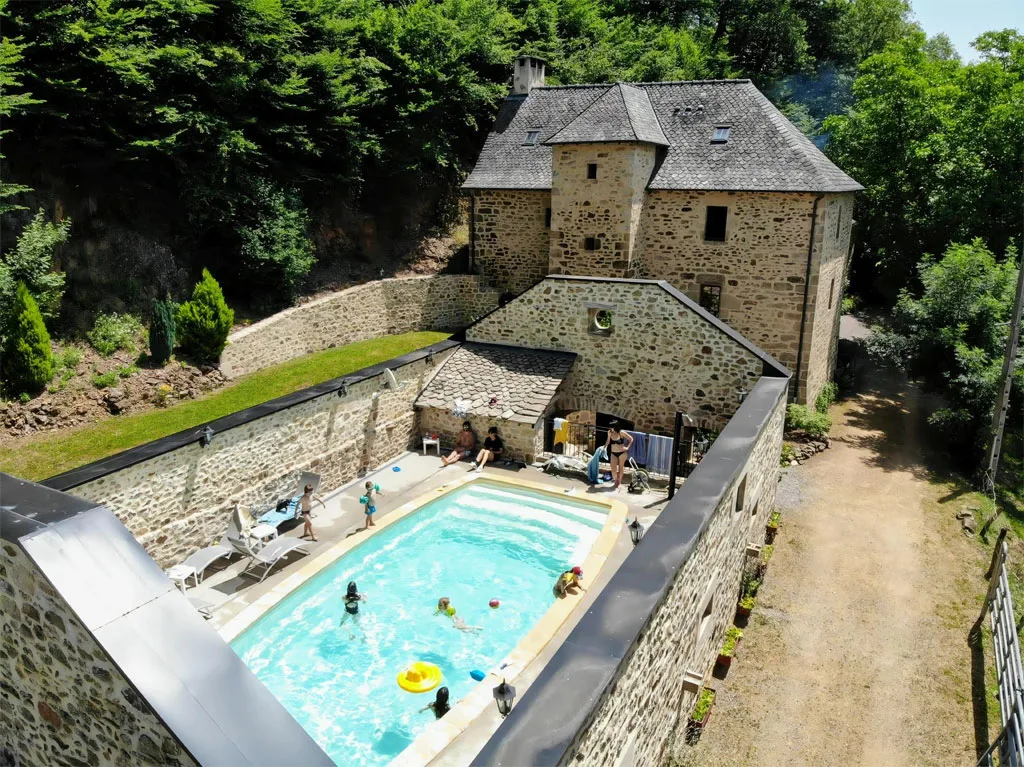 Gîte de groupe Le Charlu à Saint-Martial-de-Gimel — Vue aérienne du gîte en pierre du Limousin avec sa piscine chauffée entourée de murets, capacité 15 personnes