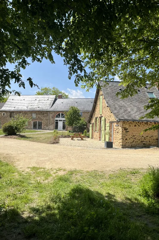 Bâtiments en pierre du gîte avec toitures d'ardoise et cour engazonnée
