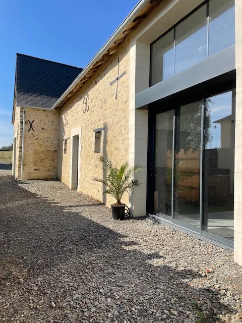 Façade en pierre du gîte avec pignon et fenêtres à volets, jardin en herbe