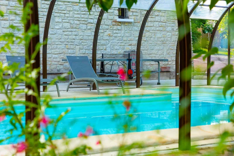 Piscine intérieure sous véranda avec tennis de table et transats