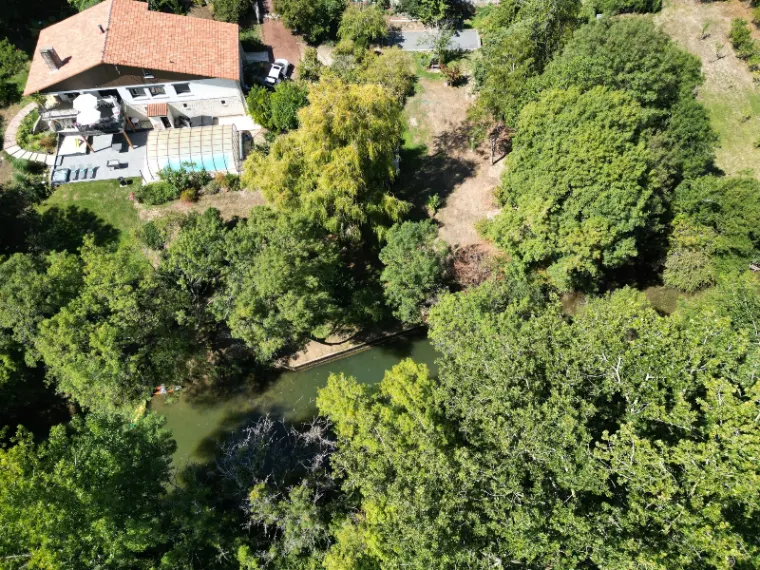 Vue aérienne de la villa avec piscine couverte, terrasses et parc arboré au bord de la Charente