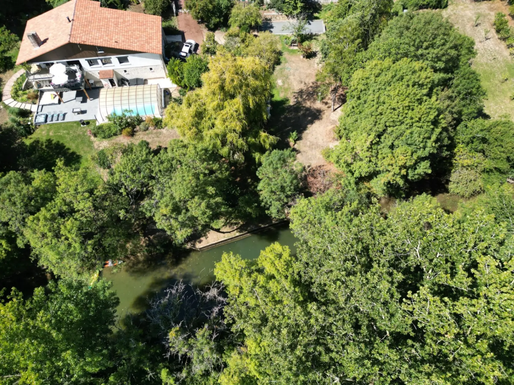 Gîte de groupe Villa des Eaux Douces à Marsac — Vue aérienne de la villa avec piscine couverte, terrasses et parc arboré au bord de la Charente, capacité 15 personnes