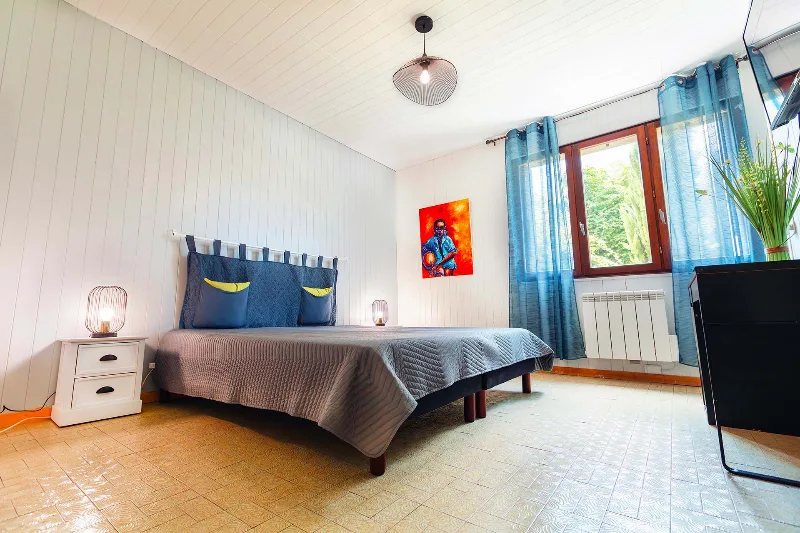 Chambre avec lit double, tête de lit capitonnée et papier peint végétal
