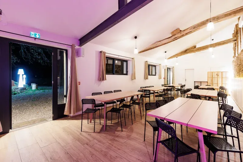 Grande salle de réception aux poutres apparentes avec longues tables en bois