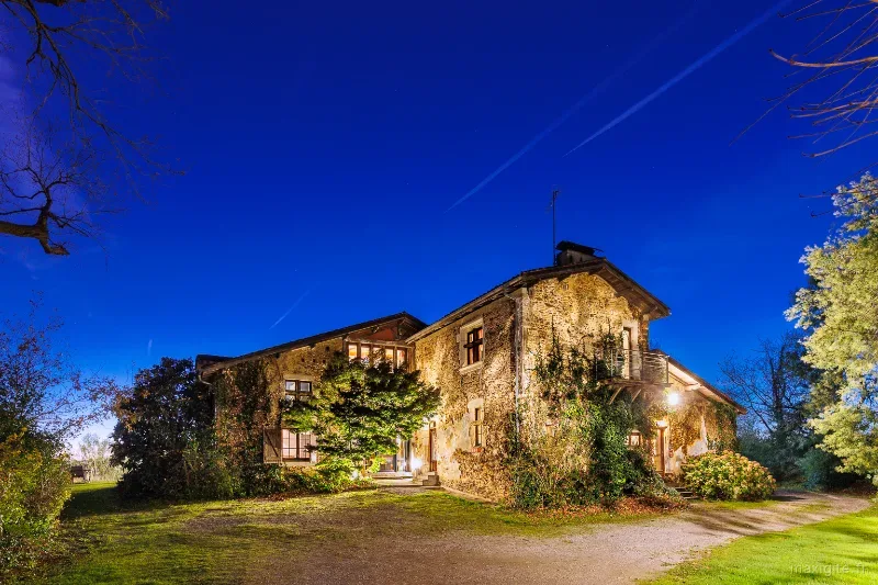 Vue latérale de la bâtisse en pierre des 17e et 19e siècles couverte de vigne vierge
