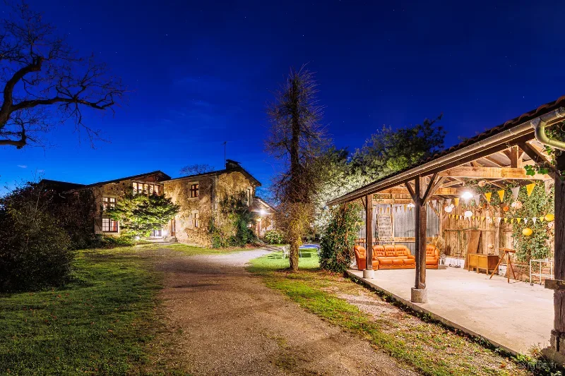 Façade en pierre du domaine de nuit avec cour arborée éclairée