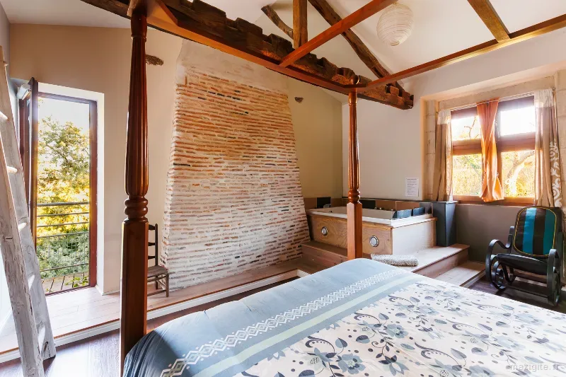 Chambre avec lit à baldaquin, jacuzzi privatif et cheminée en briques