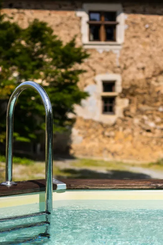Détail de la piscine avec la façade en pierre ancienne en arrière-plan