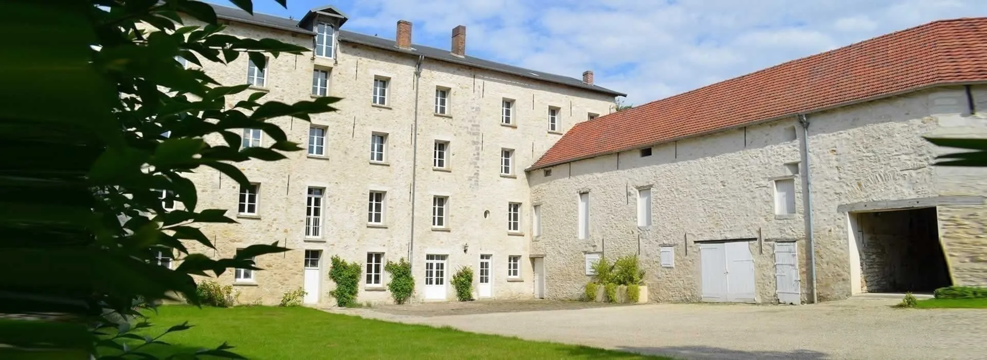Gîte de groupe Le Moulin de Saint Victor à Baron — Façade en pierre du moulin avec ses hautes fenêtres, cour et bâtiments annexes, capacité 16 personnes