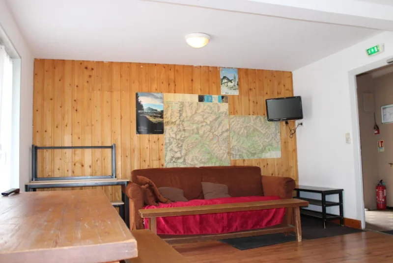 Salle commune avec canapé, cartes de randonnée et télévision