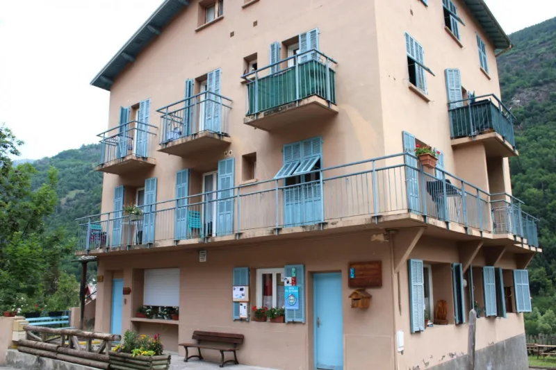 Façade du gîte d'étape communal Le Corborant, maison montagnarde aux volets bleus