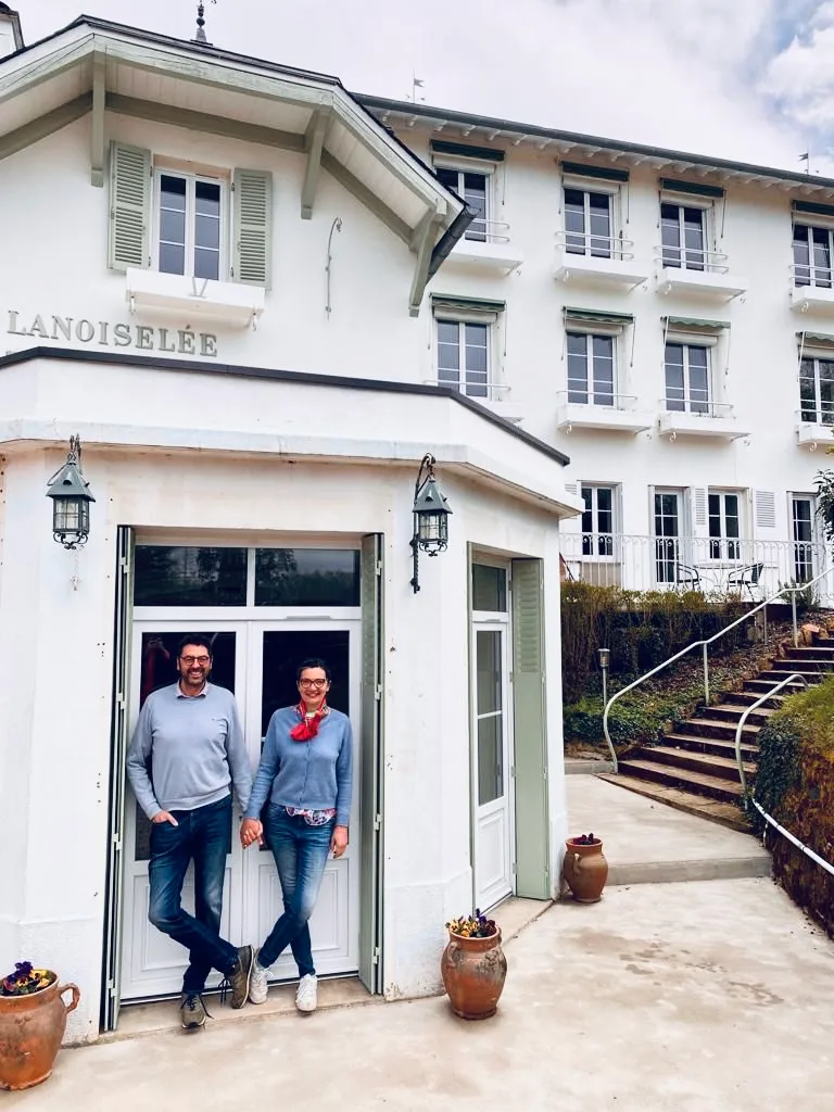 Gîte de groupe Maison Lanoiselée à Saint-Honoré-les-Bains — Façade blanche de la Maison Lanoiselée, ancien hôtel 1900 avec enseigne et terrasse d'entrée, capacité 15 personnes