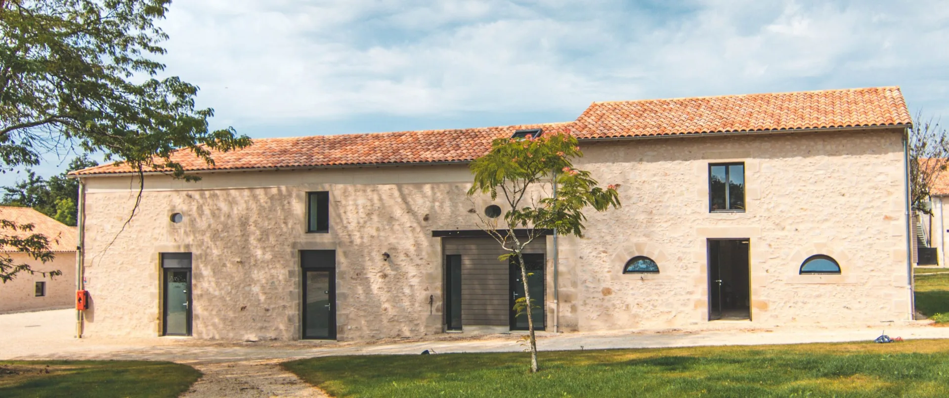 Gîte de groupe Gîte Jules - Sur les Terres de Gros Bost à Persac — Façade en pierre du gîte Jules avec entrée principale et environnement champêtre, capacité 32 personnes