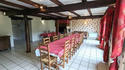 Grande salle à manger sous poutres apparentes avec longue tablée pour les repas de groupe