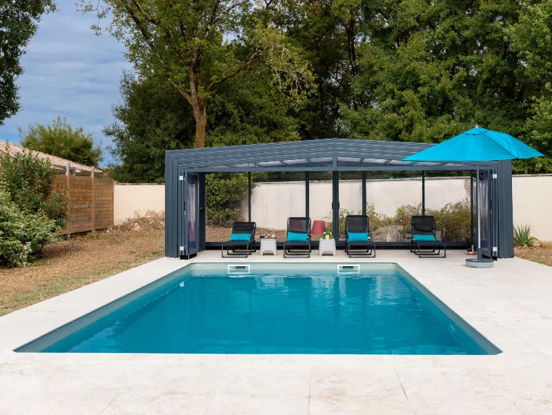 Piscine rectangulaire avec pergola bioclimatique, chaises longues bleues et parasol