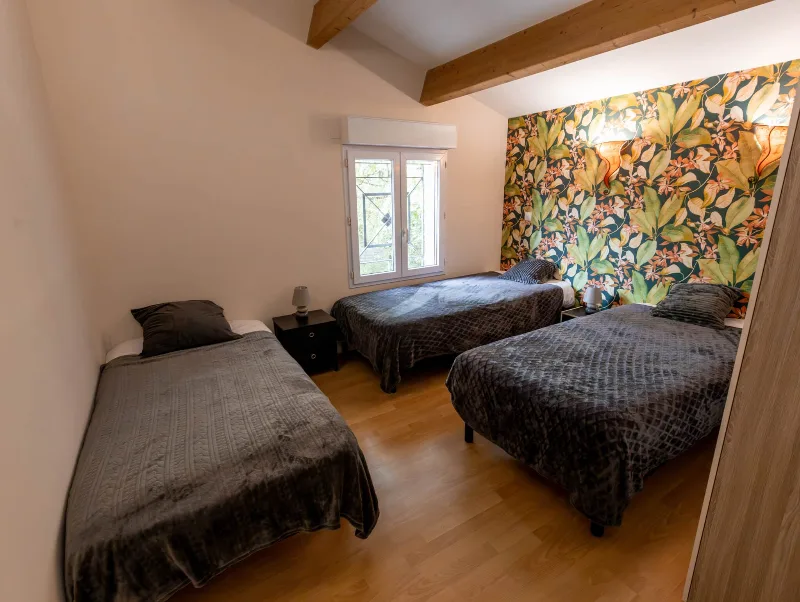 Chambre avec trois lits simples, papier peint floral et parquet clair