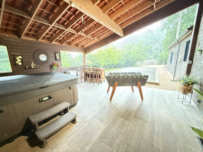 Terrasse couverte avec spa jacuzzi et baby-foot, vue sur le jardin