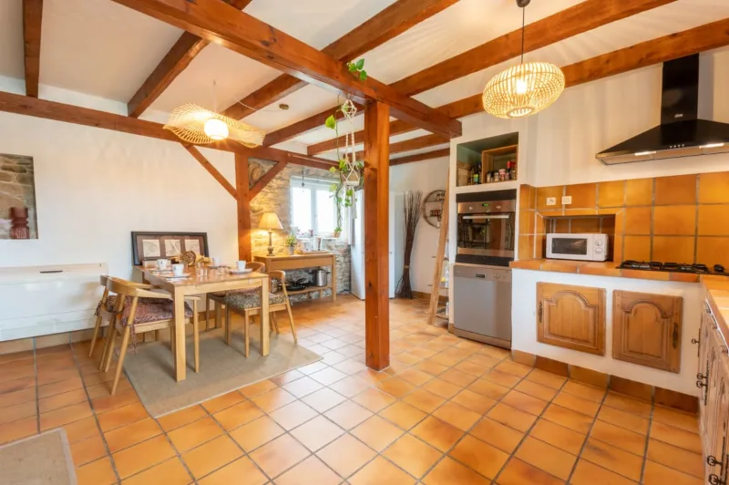 Cuisine et salle à manger ouvertes avec poutres en bois et carrelage en terre cuite