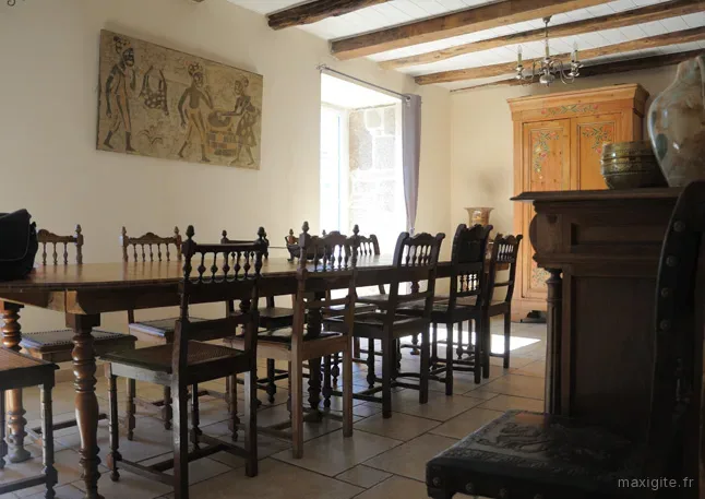 Grande salle à manger avec longue table en bois pour repas de groupe et cheminée en pierre